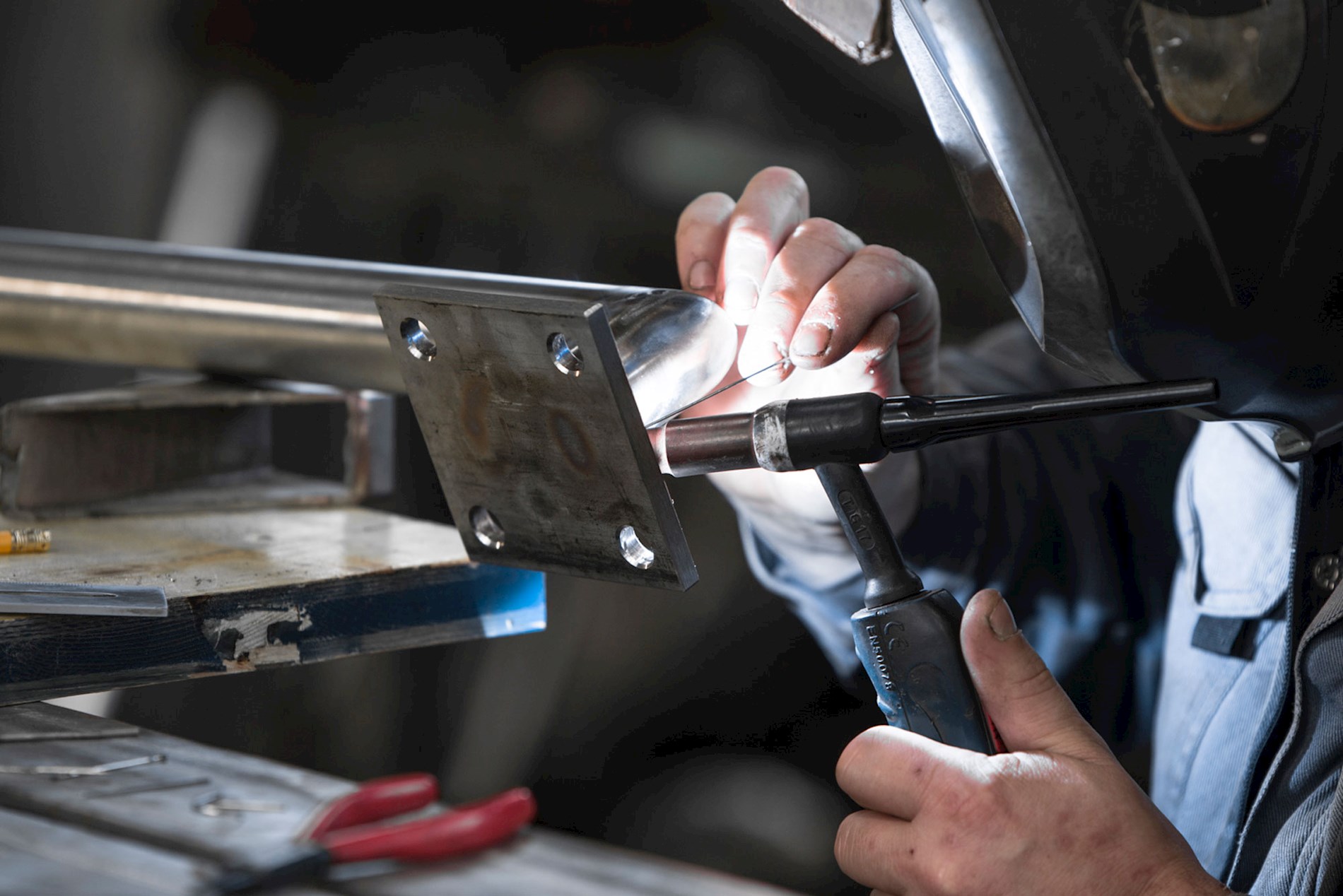 A person is welding and wearing work gloves. The welding machine produces very bright light.