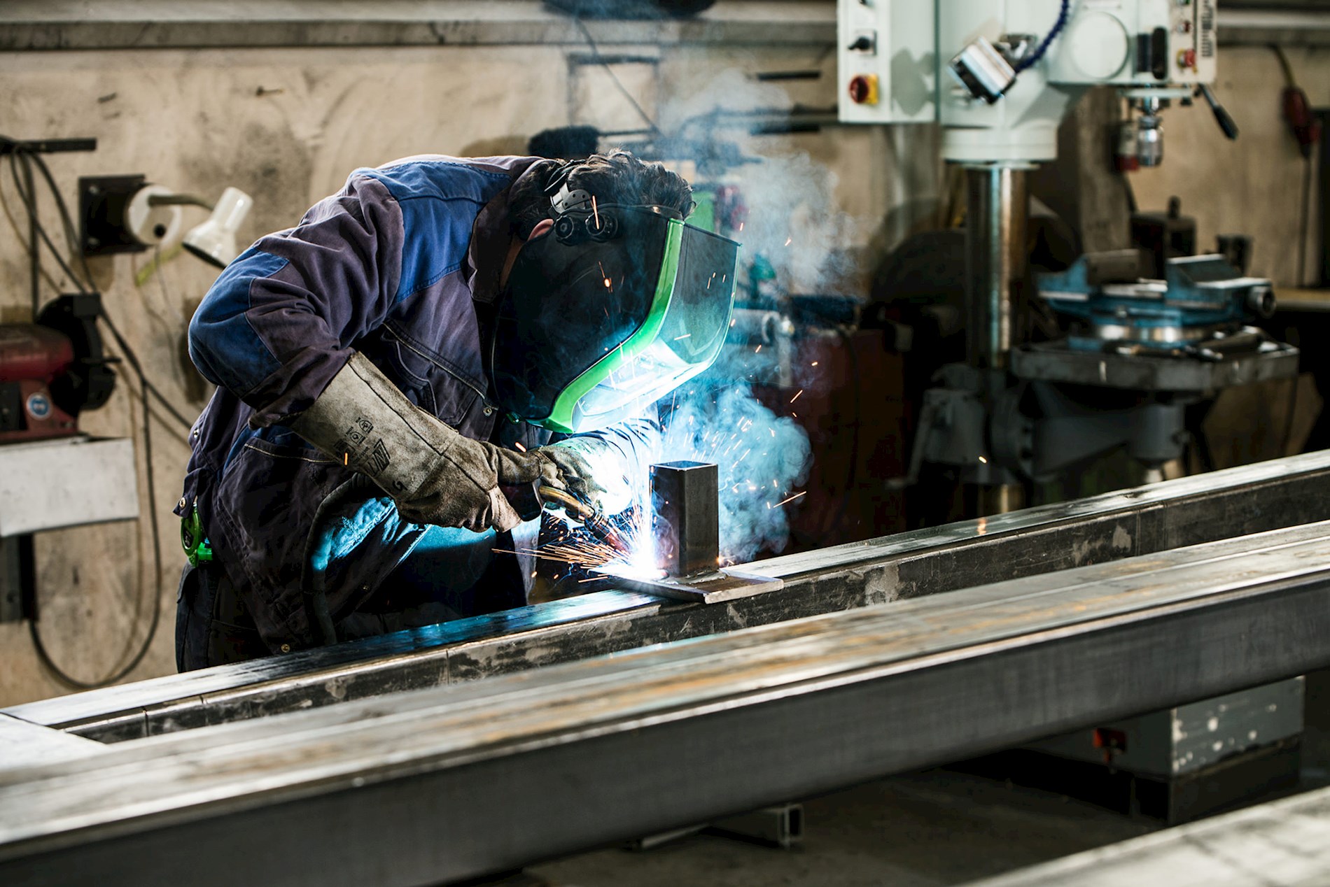 A person is welding. He is wearing a face shield to protect the eyes from the bright light.